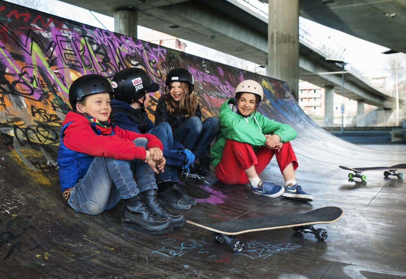 Fyra barn i en skateboardramp. Pojken närmast kameran bär ett samiskt bälte.